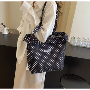Detailed shot of a black canvas tote bag with white polka dots and woven brand label