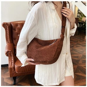 Brown corduroy crossbody bag worn by model, showing soft texture and crescent shape