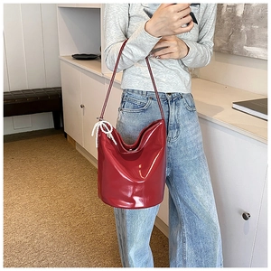 Detail of red patent leather bucket bag featuring elegant white pearl bow charm