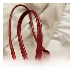 Detail of red PU leather bag handle with metal ring connection and fine stitching