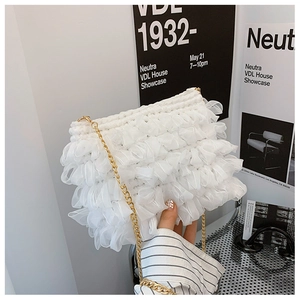 White pleated mesh cloud bag with gold chain strap shown in a modern lifestyle setting