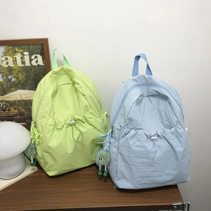 Dettaglio di zaini in nylon verde chiaro e blu con tasche a coulisse e ciondolo di peluche