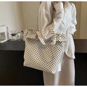Detail of white canvas tote bag with black polka dots and ruffled edges in a cafe setting