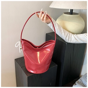 Detail of red glossy PU hobo bag with elegant pearl and gold heart charm accessories