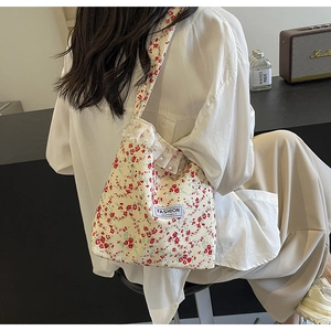 Detail of floral canvas tote bag with lace trim and pearls on a side-carrying model