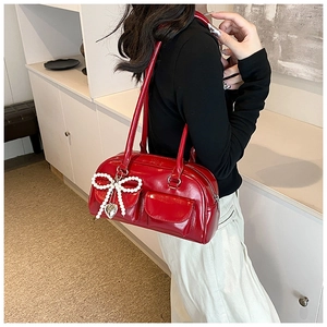 Detail view of red patent leather shoulder bag with pearl bow and silver heart charm