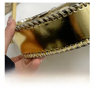 Macro detail of high-shine gold sequin bag showing precision stitching on the bottom base
