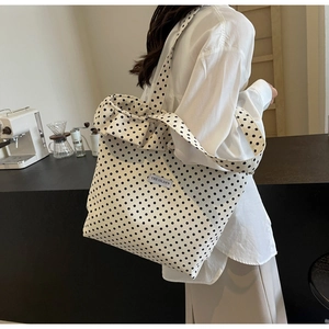 Close-up of white canvas tote bag with black polka dots and ruffle trim detail