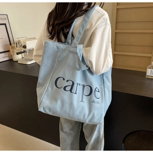 Detail of light blue canvas tote bag featuring navy carpe diem slogan print