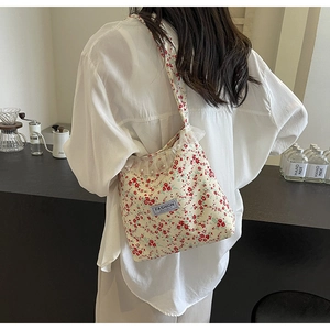 Detailed shot of floral canvas crossbody bag featuring lace trim and pearl accents