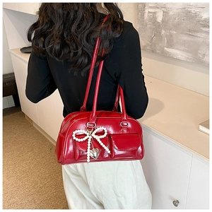 Detail of red patent leather Boston bag with pearl bow and silver heart pendant charm