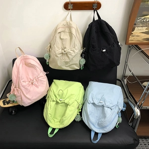 Dettaglio di zaini in nylon colorati in rosa, nero, blu e verde con simpatici pompon di pelliccia