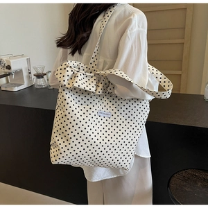 Close-up of beige canvas tote bag with black polka dots and ruffle trim detail