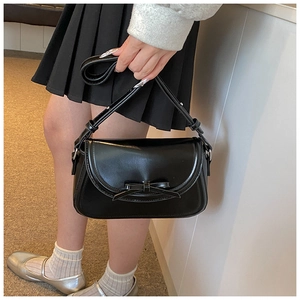 Dettaglio della piccola borsa a tracolla in pelle PU nera con fiocco decorativo sul lembo