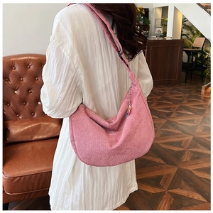 Pink corduroy crescent crossbody bag showing textured fabric and stylish tassel detail