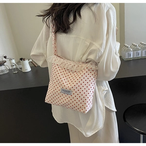 Detail of white canvas crossbody bag with red polka dots and lace pearl trim edge