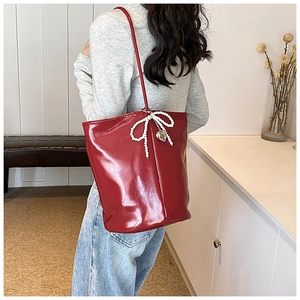 Detail of red patent leather tote bag with white pearl bow and silver heart charm