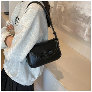 Dettaglio di una borsa a spalla in pelle PU nera con un elegante fiocco 3D decorativo