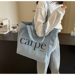 Detail of light blue canvas tote bag with letter print and wide shoulder strap