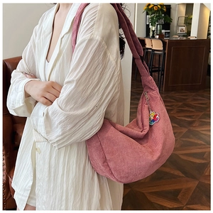 Detailed close-up of pink corduroy crescent bag with a cute bear pendant on shoulder