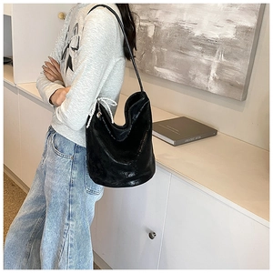 Detail of black PU hobo bag with a white pearl and bow decoration on the shoulder strap