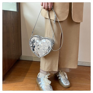 Detail showing the heart-shaped silver sequin crossbody bag with a slim leather strap