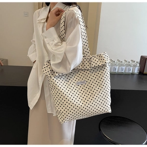 Close-up of a canvas tote bag with black polka dots and pleated ruffled edge detail