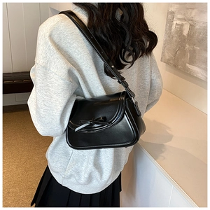 Dettaglio di una borsa a spalla a mezzaluna in pelle PU nera con fiocco indossata da modella