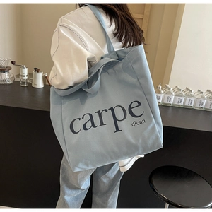 Detail of light blue canvas tote bag with black carpe dicnn text and spacious interior