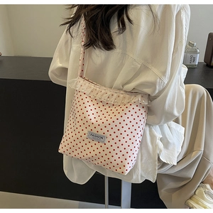 Detail of red polka dot crossbody bag with lace frills, pearls and fashion label