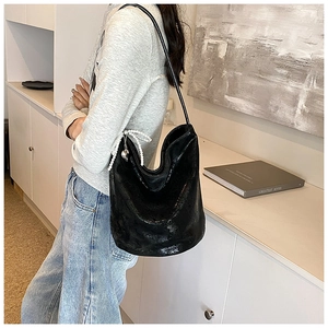 Detail of black PU hobo bag featuring pearl bow charm and minimalist shoulder strap