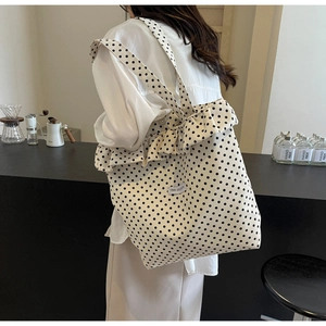 Close-up of minimalist polka dot canvas tote bag with ruffle trim and textile branding label