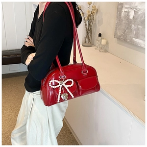 Detail of red patent leather Boston bag with pearl bow and silver heart charm decoration