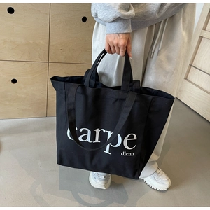 Detail of black canvas tote bag showing the carpe dicnn lettering and sturdy strap