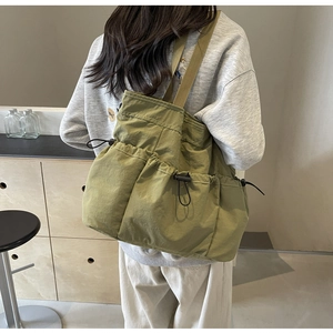 Detailansicht der olivgrünen Nylon-Umhängetasche mit mehreren Kordelzugtaschen und Textur