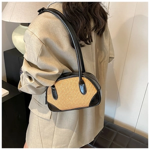 Chic straw patchwork shoulder bag worn by model in a modern minimalist indoor setting
