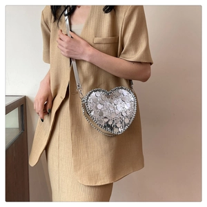 Close-up of heart-shaped silver sequin shoulder bag with metallic buckle and strap details