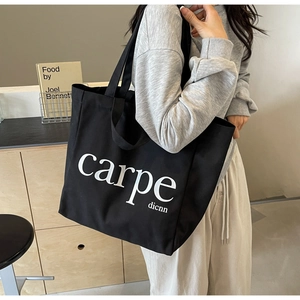 Detail of black canvas tote bag with white carpe diem lettering in a minimalist room