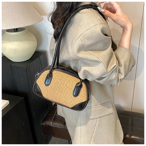 Detail view of woven straw shoulder bag with black PU leather trim and slender handle