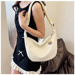 Detailed texture of white corduroy crescent bag featuring a cute bear charm pendant