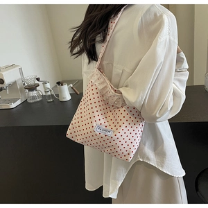 Close-up of white canvas shoulder bag with red polka dots and lace ruffle detail