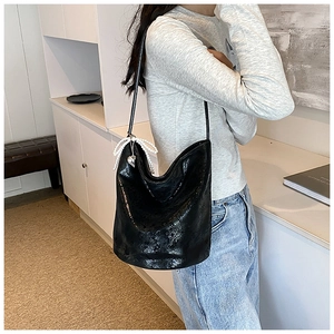Detail of black glossy PU leather bucket bag with elegant pearl bow and heart pendant