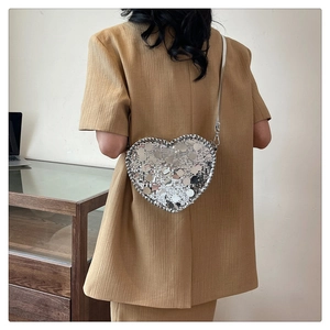 Close-up of heart-shaped silver sequin crossbody bag with woven edges and reflective texture