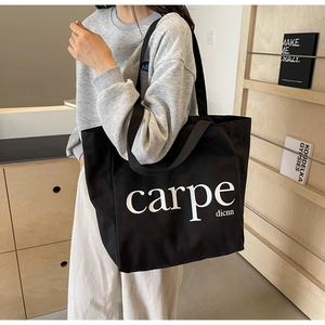 Detail of a large black canvas tote bag with white carpe dicnn graphic print