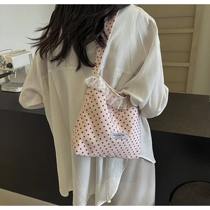 Detail of red polka dot fabric bag with delicate lace trim and pearl accents for women