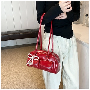 Detail of red patent leather Boston bag with pearl bow charm and metal heart pendant