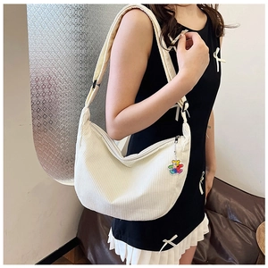 Close-up of white corduroy crossbody bag with a cute bear pendant and adjustable strap