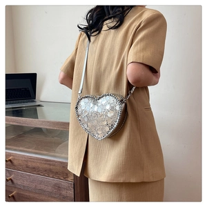 Detail of silver heart-shaped sequin crossbody bag with metallic reflective texture