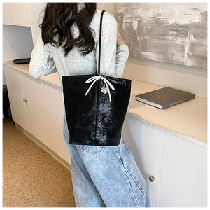 Detailed shot of black PU tote bag with pearl bow and silver heart pendant detail