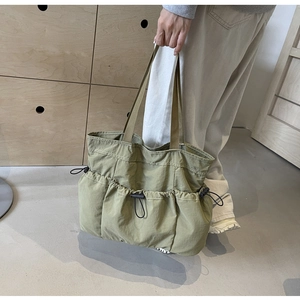 Detailansicht der grünen Tragetasche aus Wasched-Stoff mit Kordelzugtaschen und Gurtgriffen